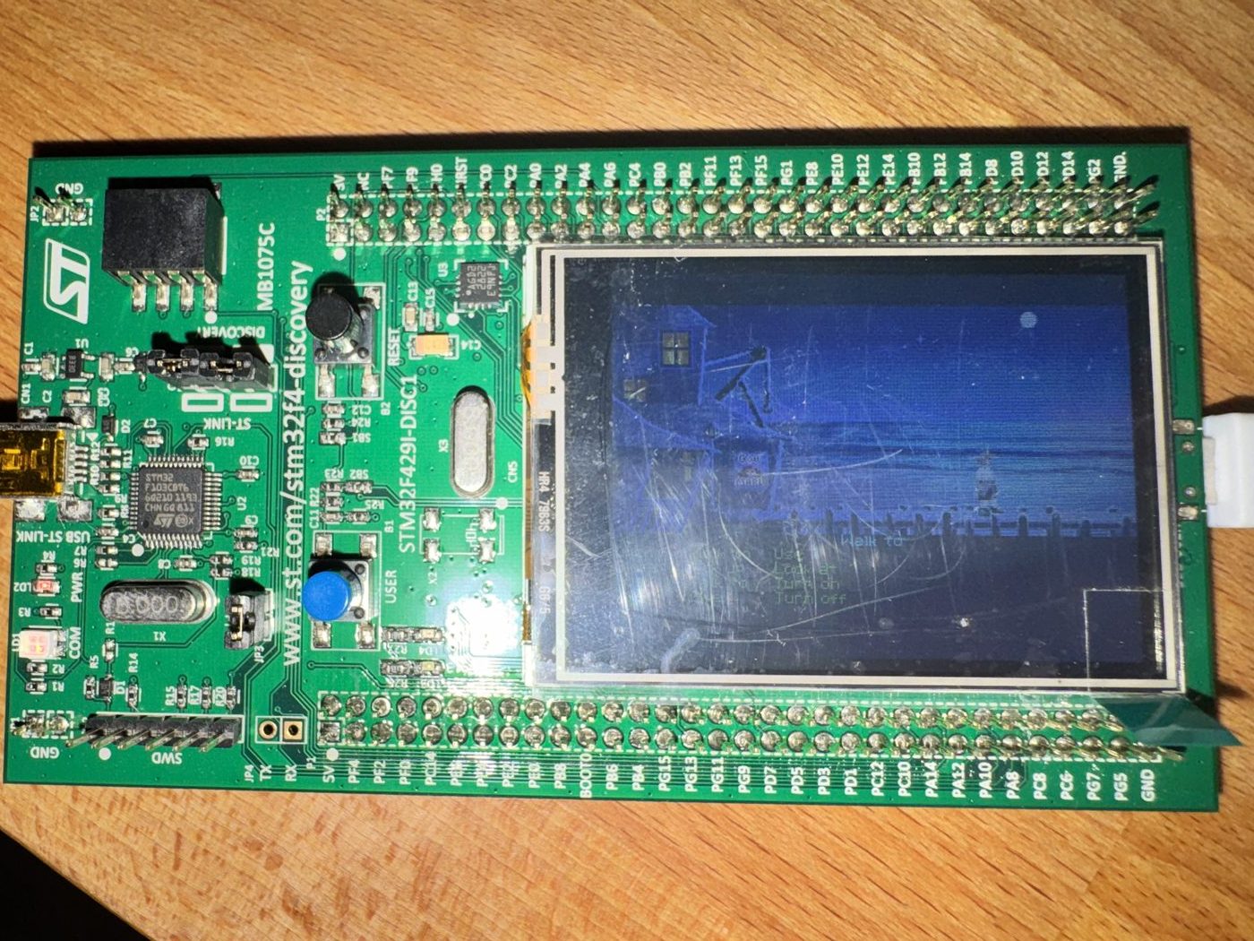 The Discovery board in landscape orientation: ST-LINK connector on the left, blue USER button and black RESET button in the middle